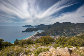 Fototapeta na wymiar Сoastline with small bays, capes, beaches and town under cloudy sky, Lycian way start, Oludeniz, Turkey