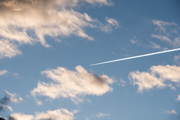 un bel cielo con nuvole arancioni al tramonto ed un'aereo che passando e lascia una scia,...