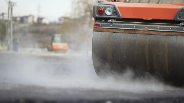 Steam compactor rollers working on the new road construction site laying new asphalt, slow motion