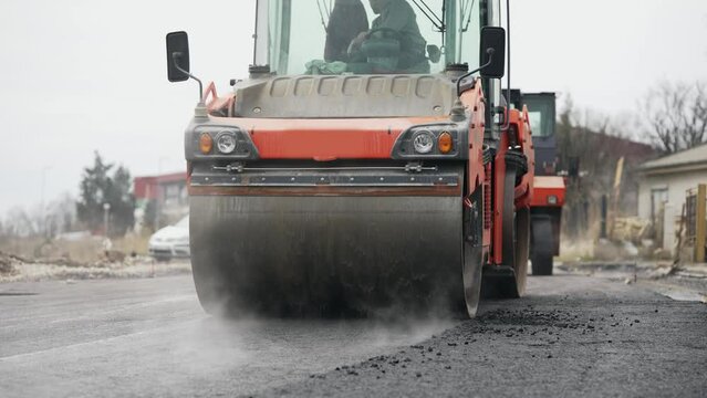 Road construction works with roller compactor machine and asphalt finisher, slow motion