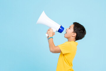Cute boy shouting on megaphone isolated on light blue background