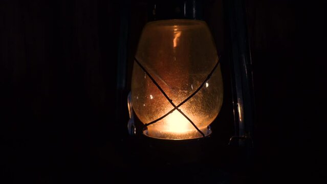 Lit hurricane warm reflected light lamp standing in a dark room. Kerosene lamp Close up views 4k video.