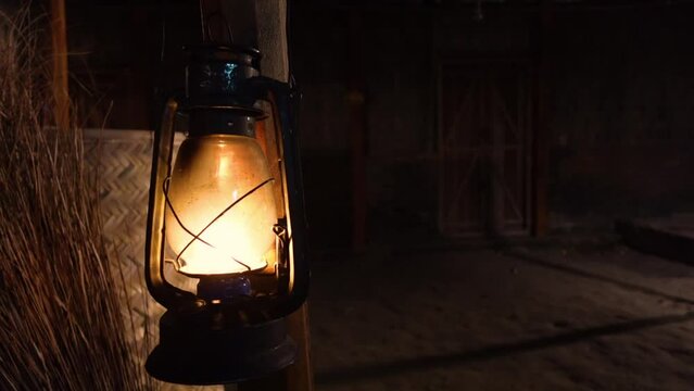 Warm light storm lantern burning at night on a wooden pillar. 