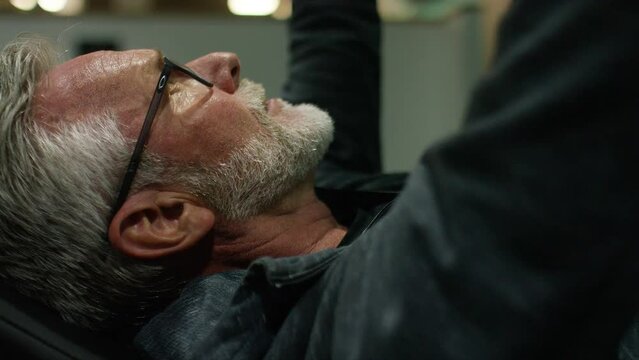 Senior male in the gym using dumb bells for his arms for a workout in the gym, in slow motion 