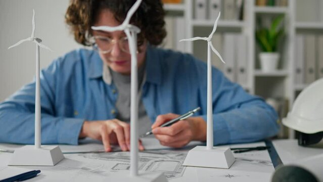 Electricity, Woman engineer In process Measuring distance on project plan drawing papers 3d model wind turbine mini mockup, Concept Specialist woman working at laptop indoors engineer Renewable energy