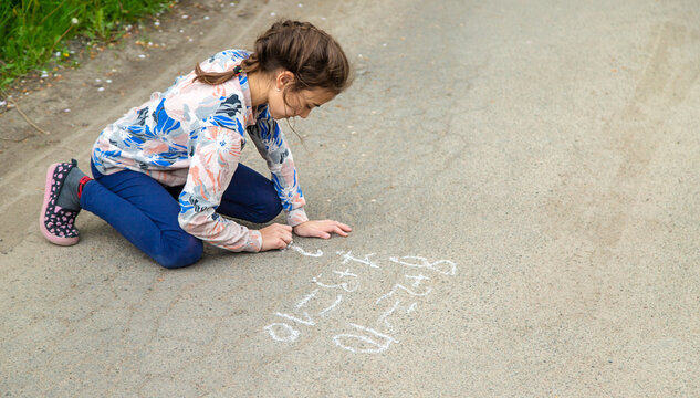 Children draw equations on the pavement with chalk. Selective focus.