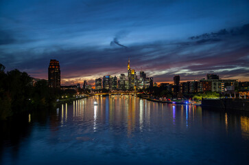 Stunning  of Frankfurt cityscape at sunset featuring skyscrapers, bridge traffic, and colorful river reflections in the background – perfect for urban backgrounds and commercials.