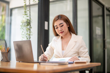 Asian businesswoman sitting in front of her considering work, office work Business woman sitting thinking work concept, Write a plan