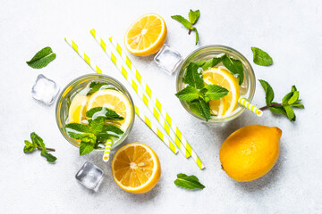 Lemonade in glass with fresh lemons and mint. Cold summer drink top view with copy space.