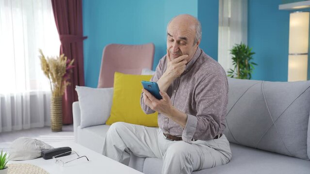An old man who is longingly video chatting with his grandchildren.