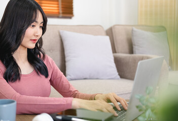 Attractive businesswoman studying online, using laptop software, web surfing information or shopping in internet store.Head shot pleasant happy young woman freelancer working on computer at home.