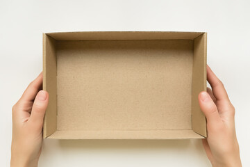 female hands holding an open cardboard box on a white background. packaging and delivery concept, top view
