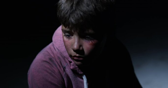Child abuse, domestic violence and portrait of a sad boy sitting in a dark room feeling alone as a victim. Children, anxiety and fear with a young male kid looking scared, lonely or in need of help