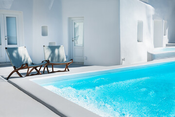 Chaise lounges near the swimming pool. White architecture in Santorini island, Greece.