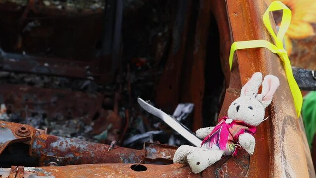 Close-up of a child's toy in ruins after a fire. A soft toy among the cars that burned down as a result of the bombing. A ruined childhood. War concept. Ukraine. Dangerous traffic accident.