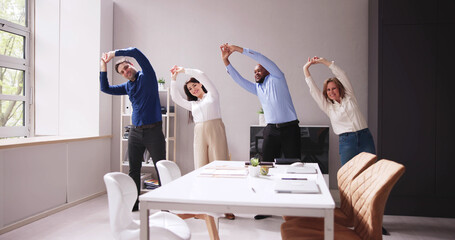 Happy Businesspeople Doing Stretching Exercise Behind Desk