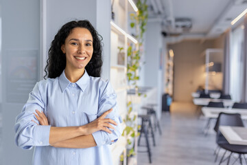 Portrait of young beautiful woman worker in cafe restaurant, Hispanic woman with curly hair and...