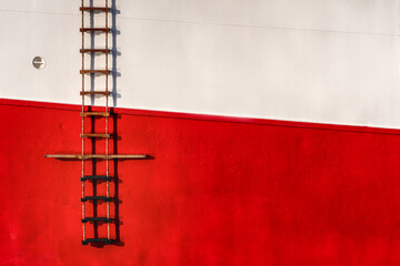 Fototapeta Steuerbordseite eines Schiffes obere Hälfte weiß und untere Hälfte rot links einer Leiter für Lotsen obraz