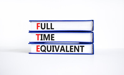 FTE Full time equivalent symbol. Concept words FTE Full time equivalent on books. Beautiful white table white background. Business and FTE Full time equivalent concept. Copy space.