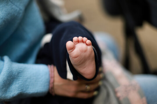 .The baby is in the arms of the mother. The newborn sleeps on the street. baby foot