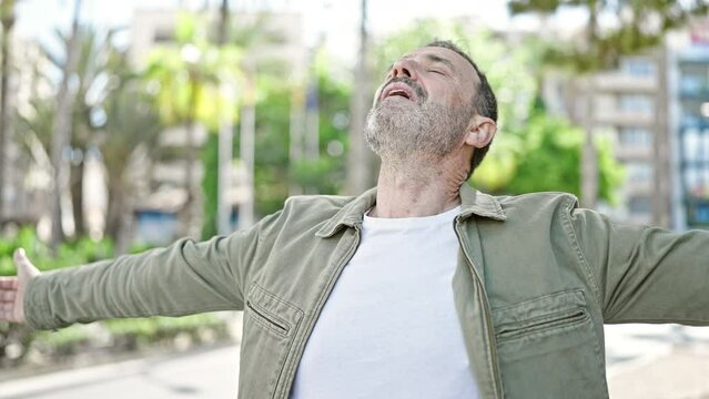 Middle age man breathing with arms open at park
