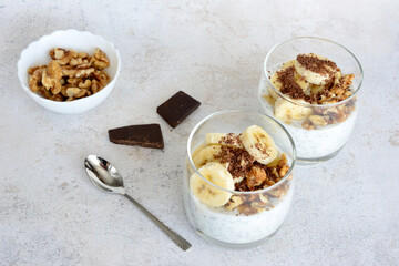 A healthy snack with chocolate, bananas, chia seeds and walnut with a spoon next to it 