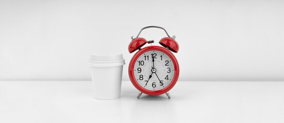 Fototapeta na wymiar Red alarm clock with cofeecup on white wall background