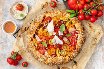 Homemade vegetable open pie galette with colorful tomatoes, ricotta cheese and fresh basil.	