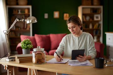 Women using digital tablet to check her finances at home office