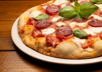 pizza with salami and tomatoes and mozzarella on the wooden table - 604399455