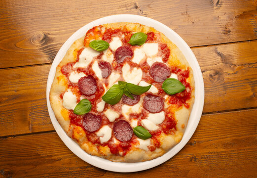 pizza with salami and tomatoes and mozzarella on the wooden table