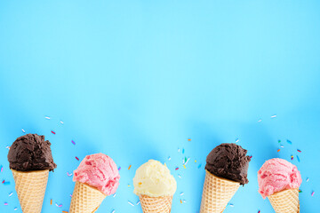Ice cream bottom border over a blue background. Dark chocolate, pink strawberry and white vanilla...