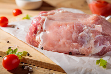 A piece of raw pork meat on a cutting board. Tomatoes, ketchup.