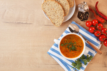Vegetable soup with potatoes, cabbage, carrots and onions in a white bowl on the kitchen table. Vegetarian food. Copy space
