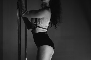 A beautiful sports dance girl holds on to a pole in the gym. Black and white shot in retro style.