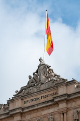 Vista de la fachada de la diputación provincial de Palencia con esculturas y bandera de españa.