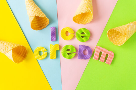 Flat lay composition with a waffle cone and the inscription ice cream on different bright backgrounds. View from above.
