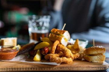 Various beer snacks on the table close-up. Mini burgers, onion rings, sausages, fried potatoes and other beer snacks