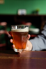 Unrecognizable person holding glass with cold beer in the bar