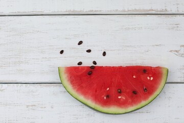 Fototapeta na wymiar A slice of watermelon, black seeds, on a white wooden table, hello summer, vitamins, photo background