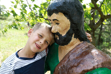 Child posing with wooden statue of hero