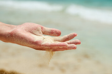 Fototapeta na wymiar Beach sand falls from a hand of a woman.