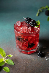 Cold berry lemonade with ice for a hot day. With a backdrop of wood and moss. 