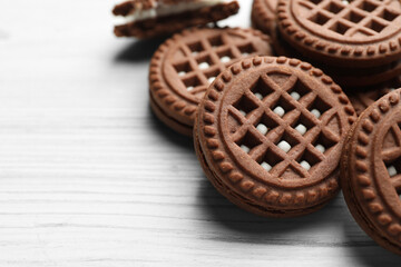 Tasty chocolate sandwich cookies with cream on white wooden table, closeup. Space for text