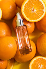 Cosmetic bottle product serum vitamin C with orange and lemon flat lay on yellow background, top...