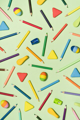 Colored Pencils and rubber erasers background pattern on light green. Back to School or drawing and creativity concept. Copy space in center. Top view