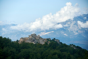 A breathtaking view of Tlos, Turkey: ancient ruins surrounded by lush forest and majestic mountains in the clouds.