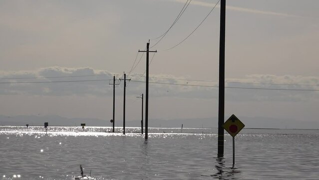 2023 - Excellent aerial view of a flooded road, with powerlines and road signs sticking out of the water in Corcoran, California.