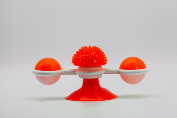 An orange plastic cat toy with two balls with white background.