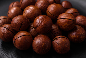 Delicious roasted macadamia nuts in shell on a dark textured background